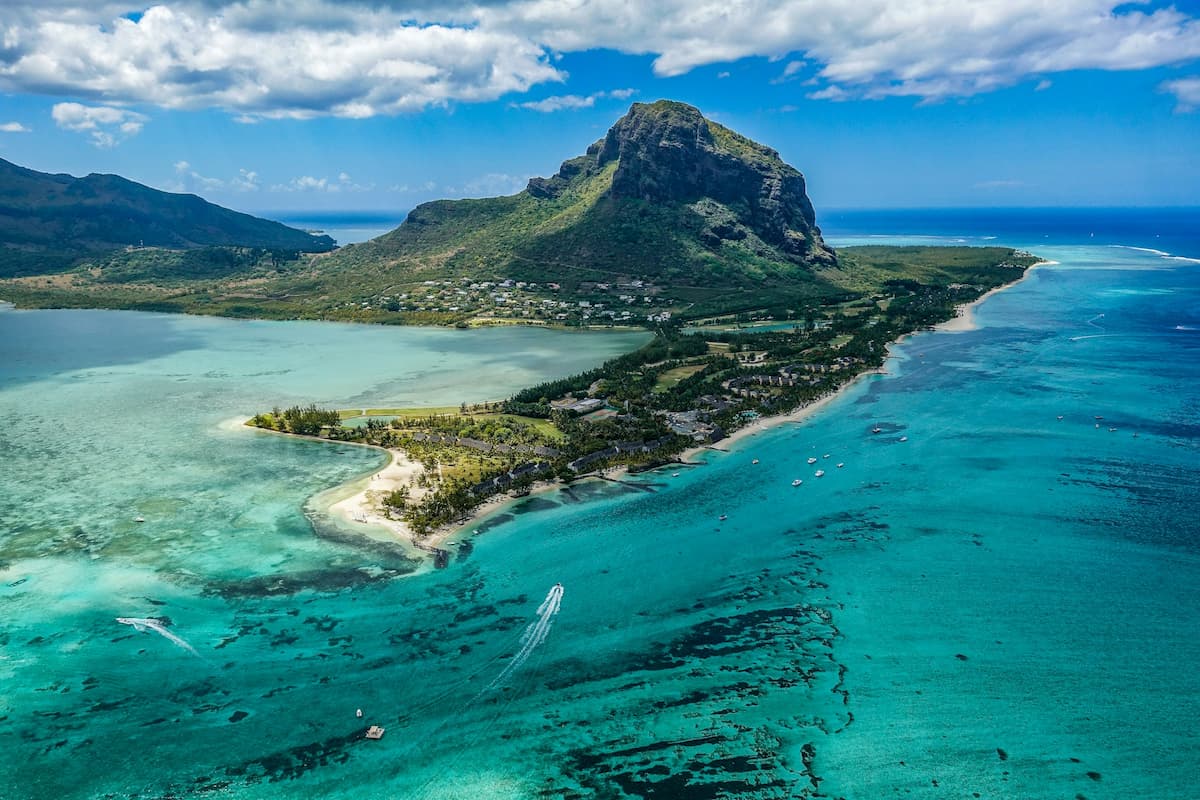 Imagem de longe de uma praia com uma montanha no fundo