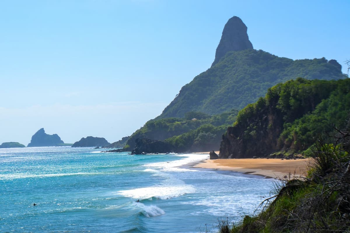 Imagem de uma praia com uma montanha no fundo 