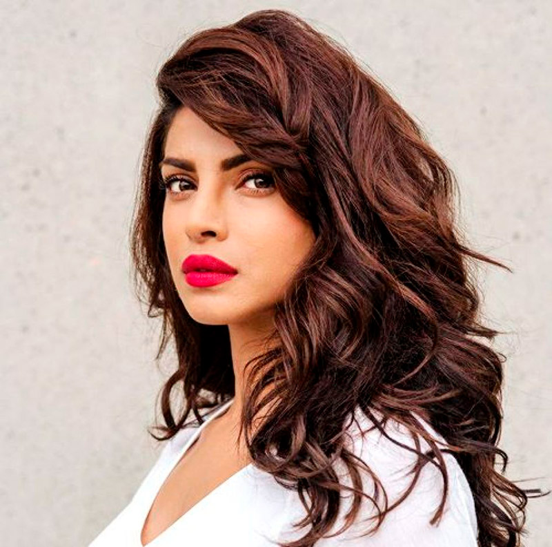 Mulher de cabelo solto, batom vermelho e camiseta branca.