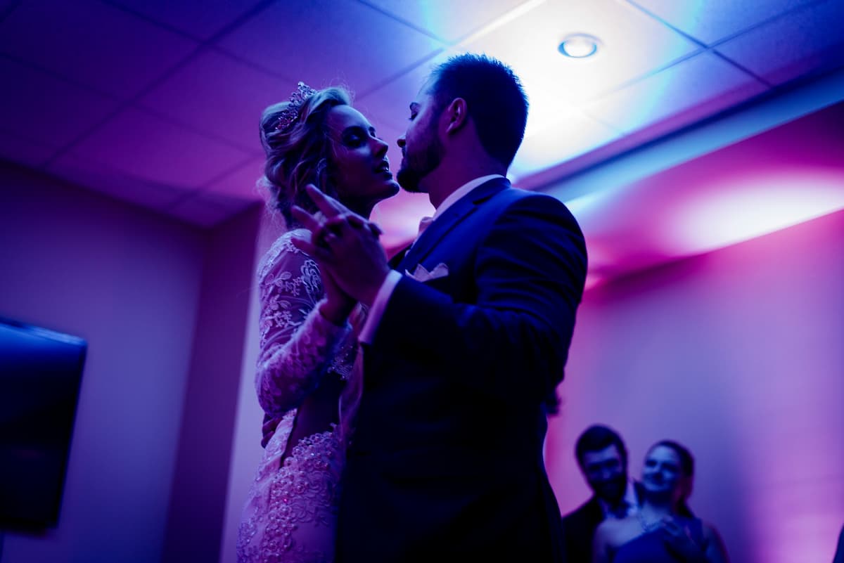 Imagem de um casal dançando no casamento com uma luz rosa no ambiente