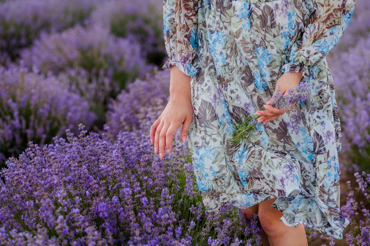 Imagem de uma mulher com vestido estampado em um lugar com flores lilás