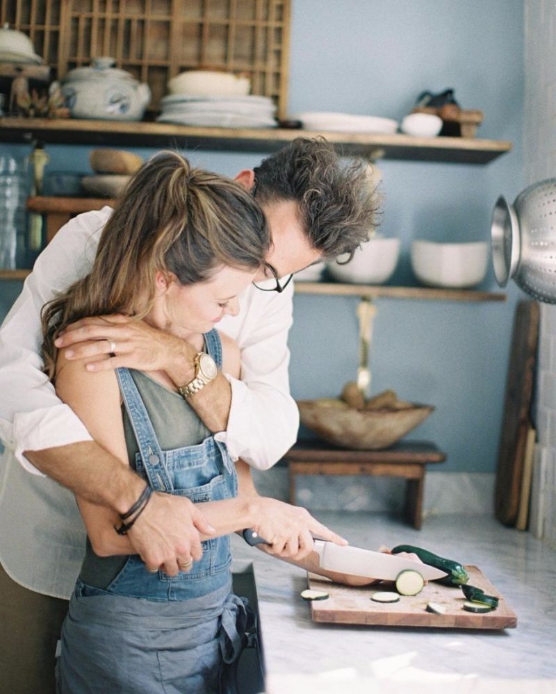 Casal se abraçando enquanto cozinham juntos 