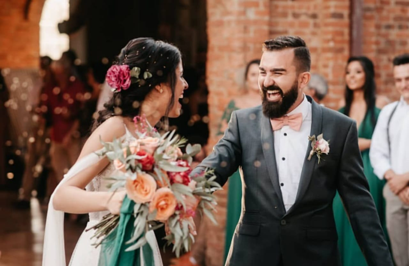 foto de casal composto por homem usando terno cinza escuro e mulher com vestido de noiva durante a festa do casamento