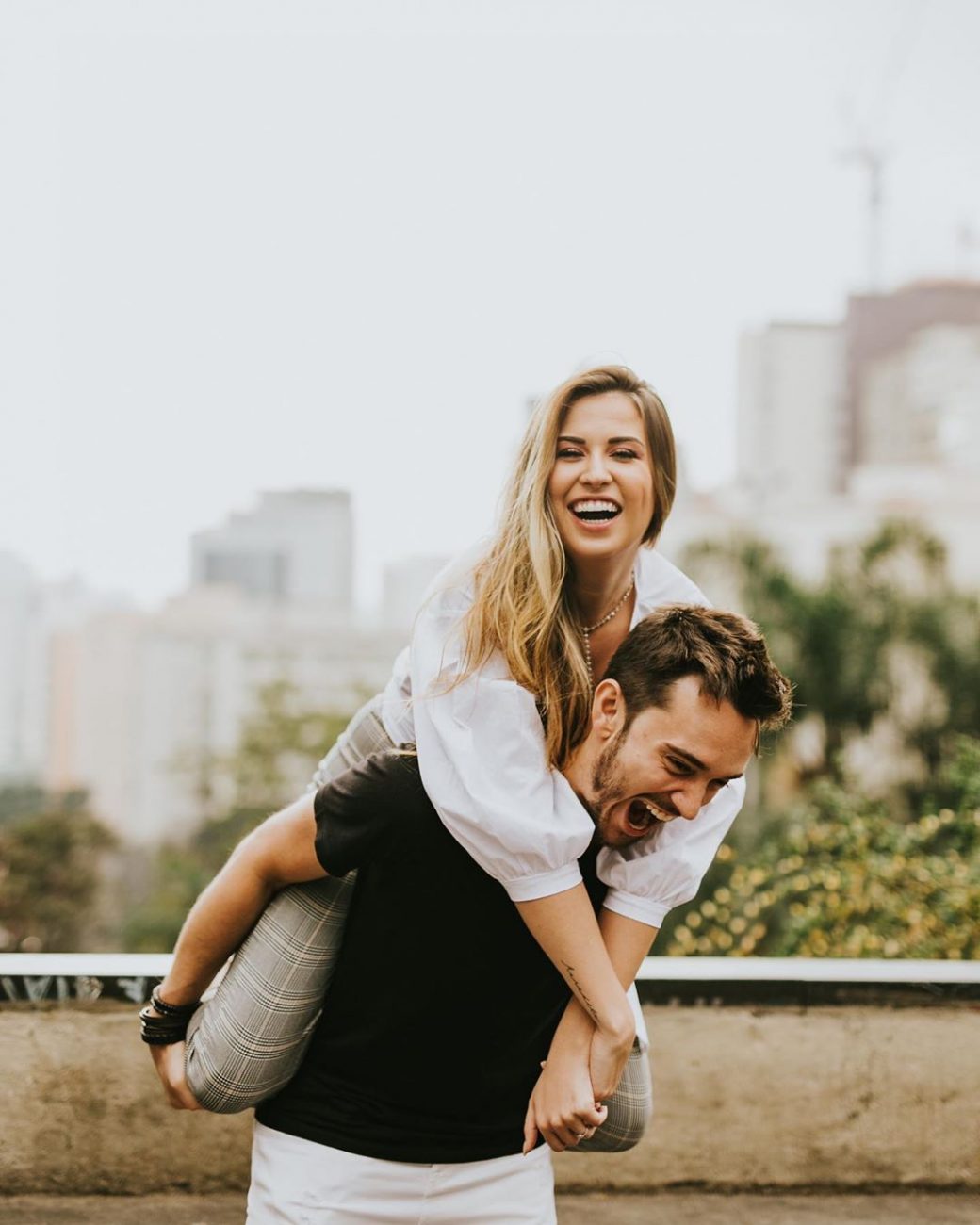 Casal se divertindo e rindo com ela nas costas dele