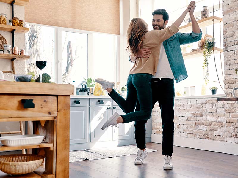 Romance. Full length of beautiful young couple in casual clothing dancing and smiling while standing in the kitchen at home