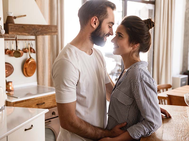 Image of adorable brunette couple in love man and woman 20s smiling while hugging together in apartment