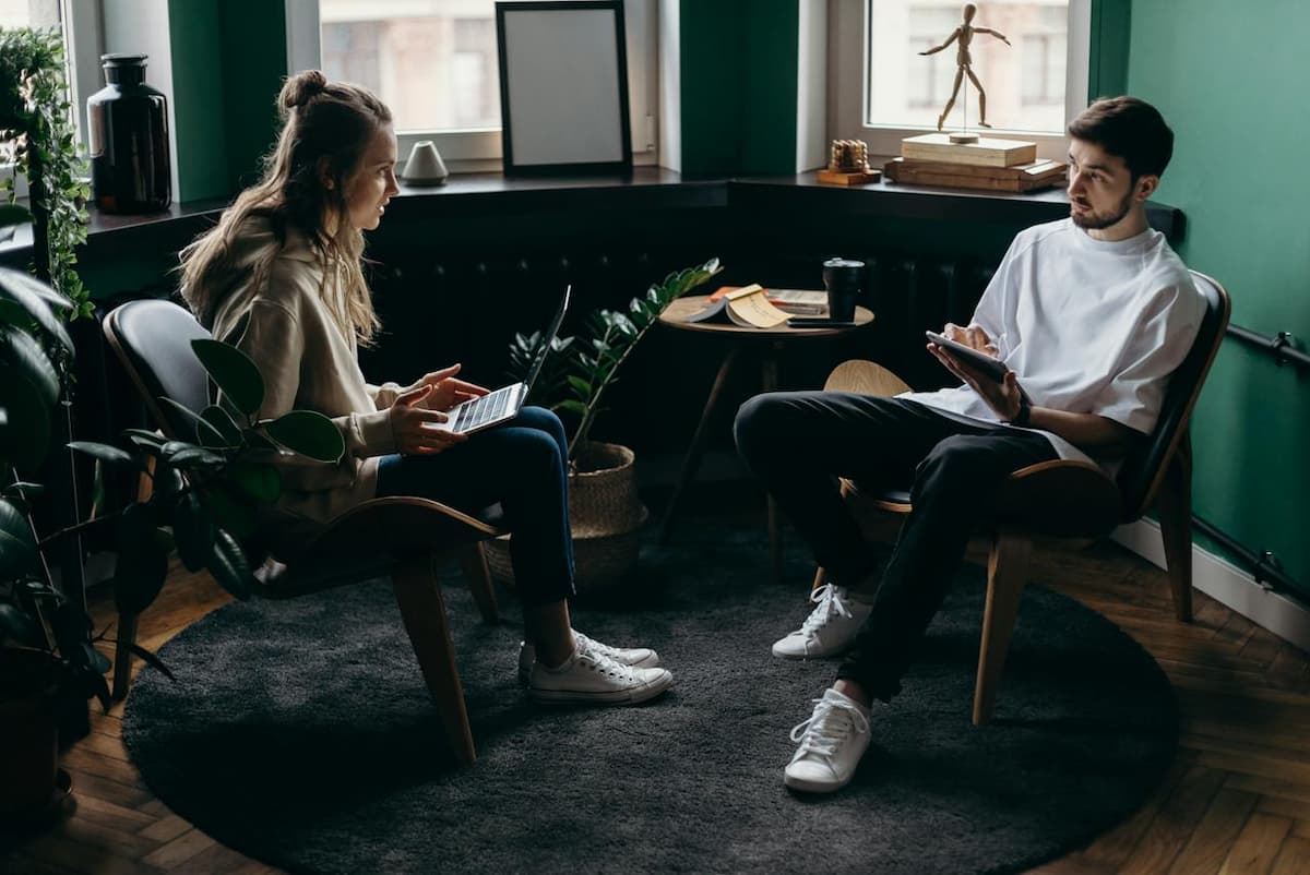 Imagem de um casal sentados mexendo no computador no quarto