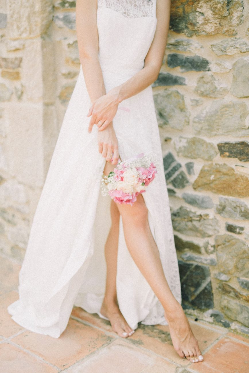 Mulher vestida de noiva, em pé, enquanto segura um buquê. Imagem disponível em Pexels.