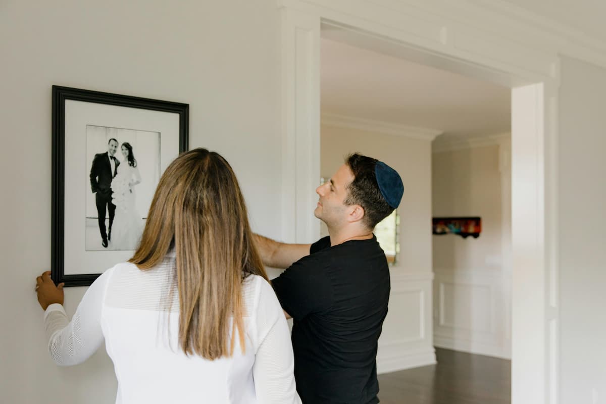 Um casal pendurando o porta retrato na parede