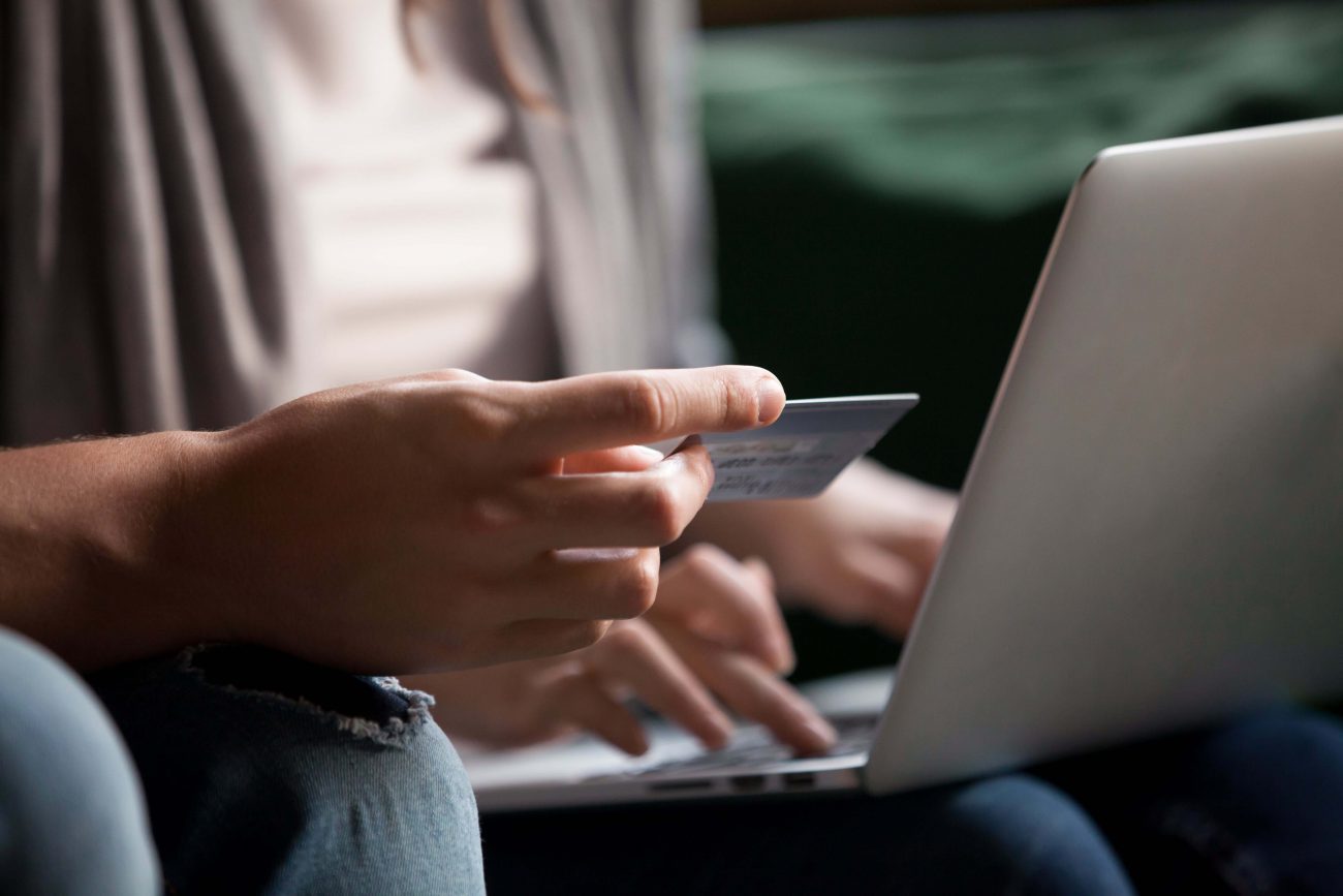 Mulher segurando cartão de crédito em frente ao computador