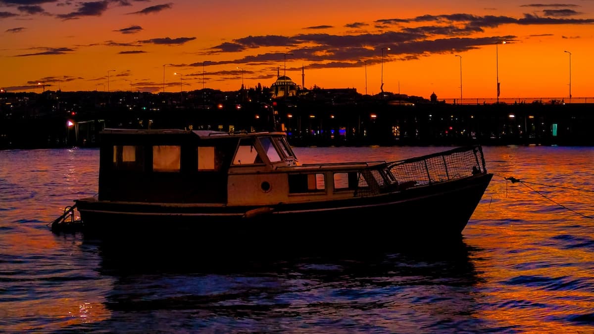Imagem de um barco navegando sob um pôr do sol