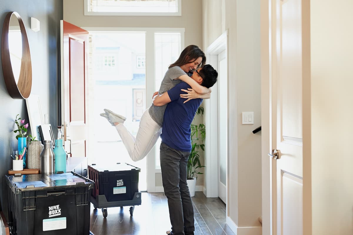 Imagem de um casal abraçados na porta da casa