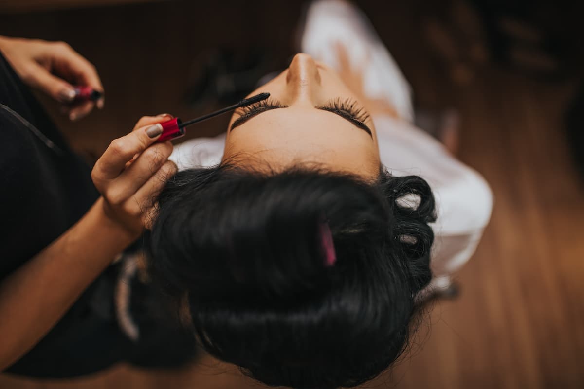 Mulher na cadeira sendo maquiada e fazendo penteado