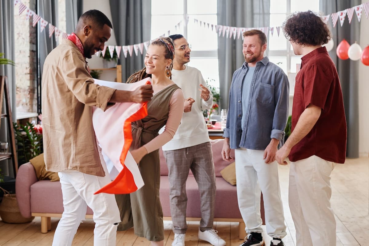 Amigos em uma festa em casa com um homem ganhando um presente de uma mulher
