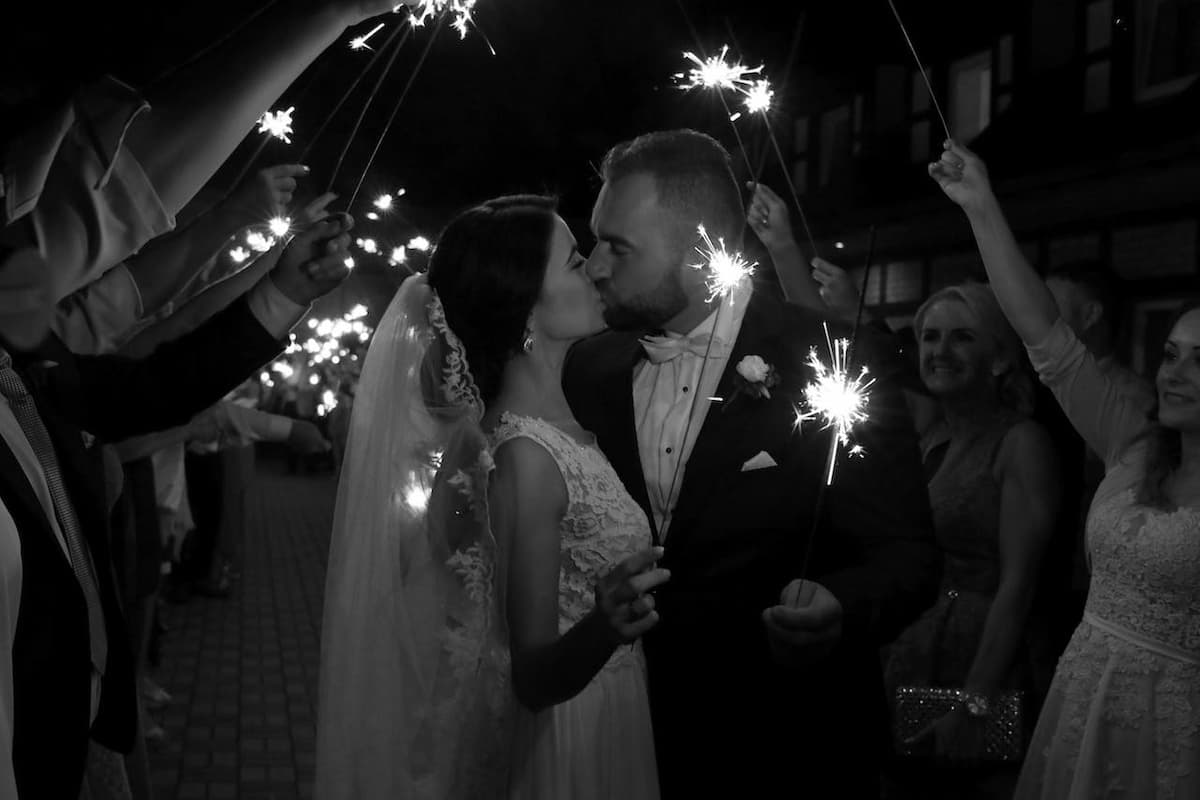 Casal se beijando no dia do casamento com as pessoas ao redor