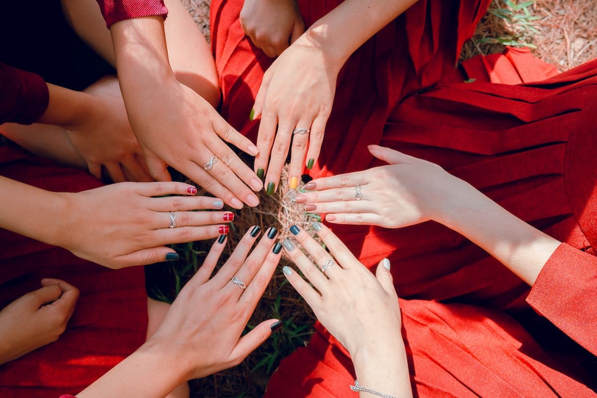 Mãos femininas com anéis iguais e unhas coloridas