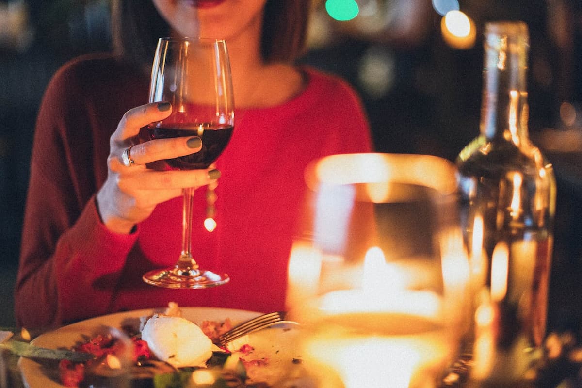 Mulher com taça de vinho em um jantar com velas
