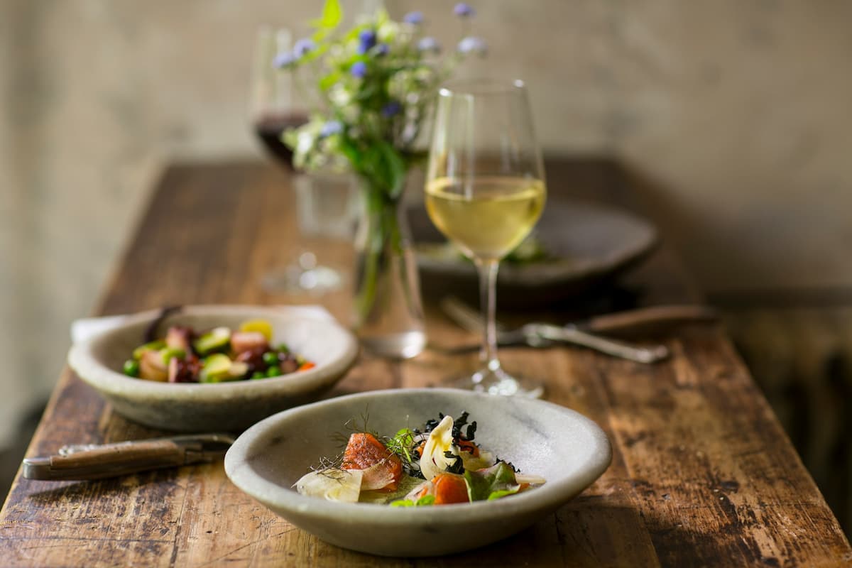 Imagem de um jantar em uma mesa de madeira com uma taça de vinho