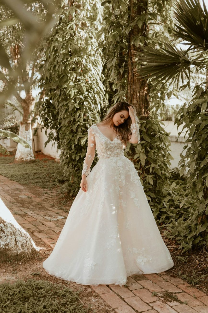 Imagem de um mulher com vestido de noiva na frente de arbustos