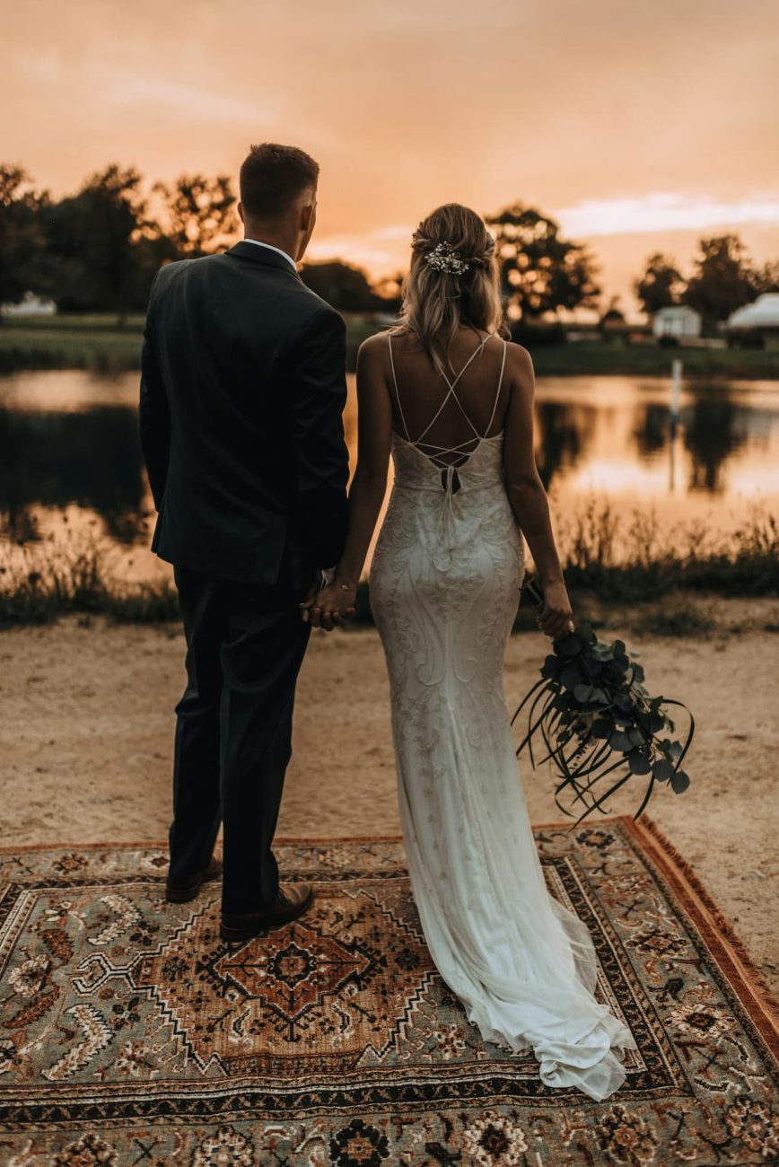Imagem de um casal de costas com a mulher usando um vestido de noiva com formato de sereia