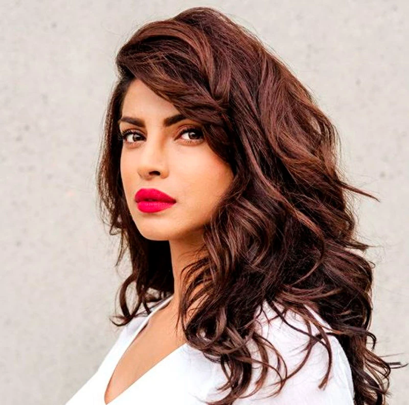 Mulher de cabelo solto, batom vermelho e camiseta branca.