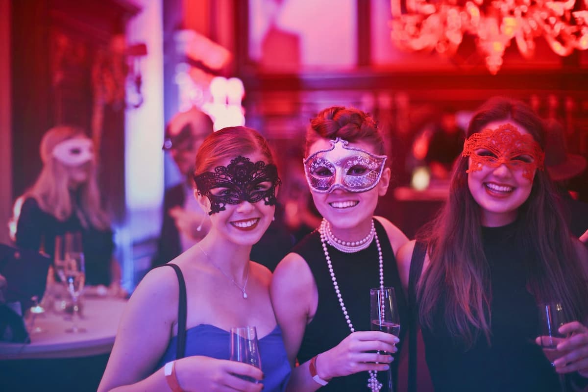 Duas amigas de máscara em uma festa temática|Imagem de discos de vinil na parede|Imagem de uma festa na piscina em um dia de sol|Imagem de uma mulher tomando uma taça de vinho|Imagem de um jardim iluminando com presentes na árvores|Imagem baldes de pipoca|Imagem de quatro cupcake azul|Imagem de uma mesa e parede branca com itens de decoração de viagem|Imagem de uma menina jogando arcade|Imagem de abacaxis com itens de decoração de verão|Imagem de uma ampulheta