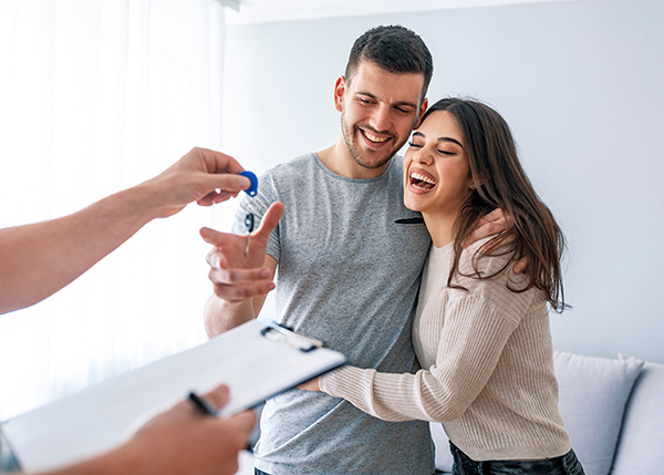 |casal jovem se abraçando com caixas ao fundo e segurando uma chave|casal de homem e mulher negros felizes e sorrindo. Ele está empurrando ela dentro de uma caixa||Casal jovem pintando a parede||