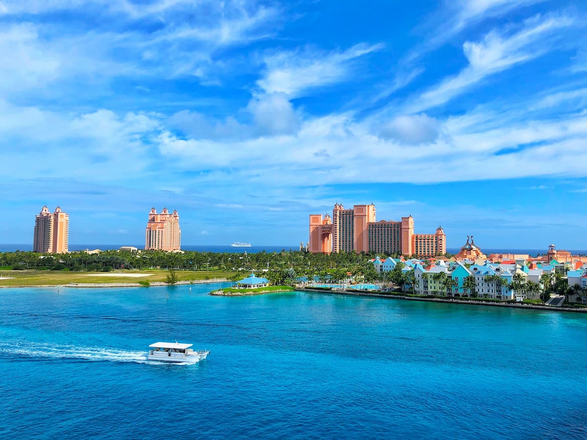 Barco branco no mar perto de edifícios durante o dia||||||Litoral das Bahamas durante o dia|Duas pessoas deitados na areia branca de uma praia durante o dia|Mulher de óculos de mergulho em baixo d'água|Imagem da praia com areia branca e o mar ao fundo durante o dia|Imagem do Hotel The Royal at Atlantis nas Bahamas com água na frente durante o dia