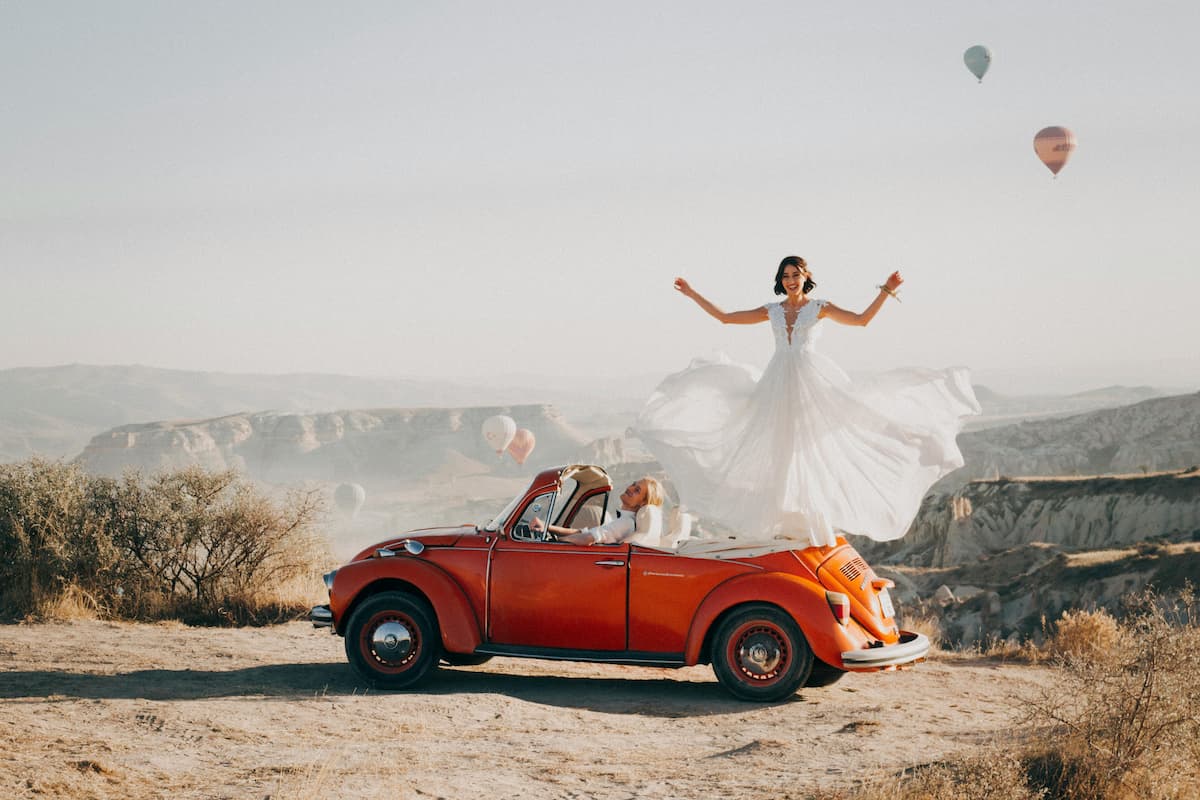 Noiva em cima de carro antigo tirando foto para casamento vintage.|||
